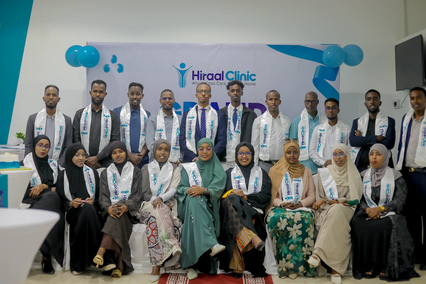 The wider Hiraal Clinic team photographed together in front of the clinic's branding